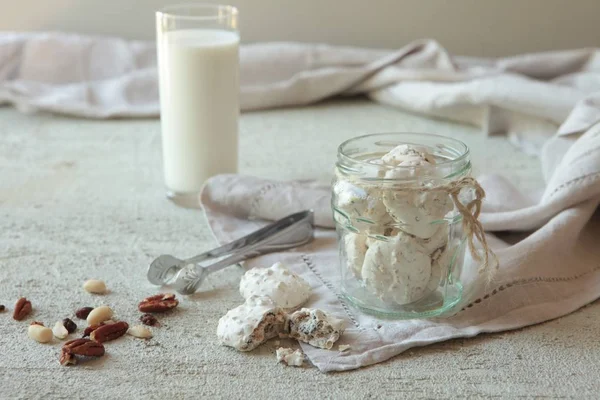 Traditional Beze or Meringues with nuts in a glass jar on concrete background. Copy space. A glass of milk. Homemade Meringue made with love. — Stock Photo, Image