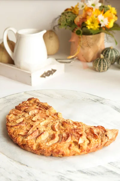 Freshly baked apple pie with apples in the background.