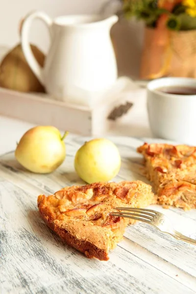 Freshly baked apple pie with apples in the background.