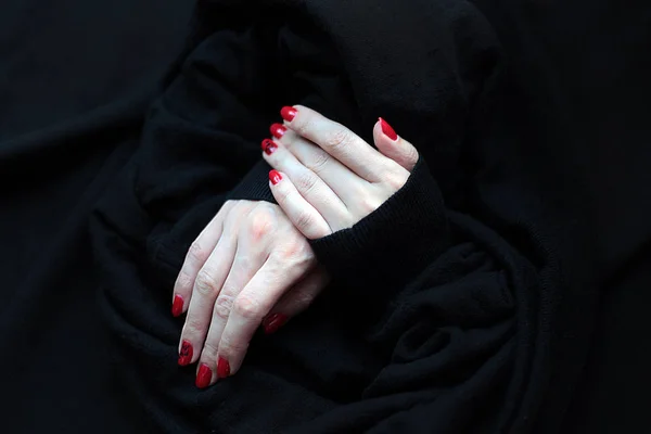 Chiodi rossi e le mani isolate su sfondo nero pelliccia Foto Stock