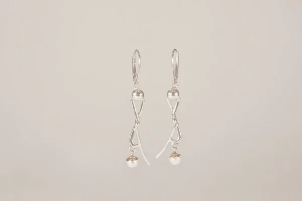 Two beautiful silver earrings on white backdrop — Stock Photo, Image