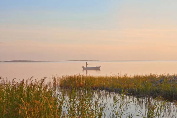 Visser aan de boot op roze zonsondergang zee. silhouet van vissers met zijn boot. Prachtige zonsondergang hemel met blauwe en roze kleuren. — Stockfoto