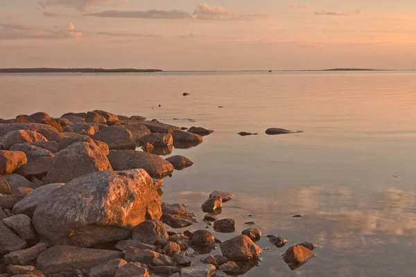 Zonsondergang aan de kust van de Oostzee in Estland bij Haapsalu stad met rotsen op de voorgrond. rotsen en stenen op de kalme zee en roze zonsondergang hemel. — Stockfoto