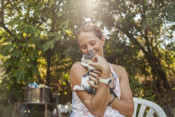 Bebek kedi tutan güzel kadın. Raylight ağaçlar aracılığıyla. Doğal peyzaj