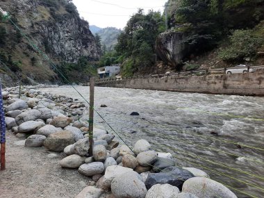 Neelum Vadisi 'nin pitoresk Kundal Shahi bölgesinde hızla akan bir şelalenin çarpıcı gündüz manzarası..