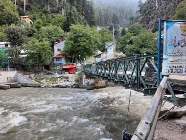 Neelum Vadisi 'nin pitoresk Kundal Shahi bölgesinde hızla akan bir şelalenin çarpıcı gündüz manzarası..