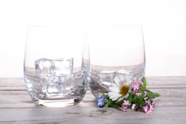 Masada çiçekli buz küplü iki boş bardak.