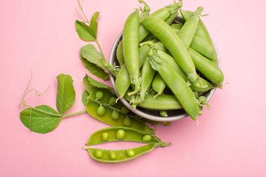 Taze yeşil şekerleme, tatlı bezelyeler kabın içinde fotokopi alanı açık pembe arka plana yakın