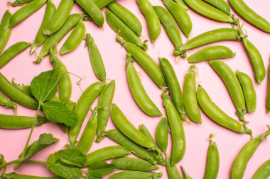 Taze yeşil şekerleme, tatlı bezelye fotokopi alanı açık pembe arka planda düz konsepte yakın.