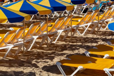 Birçok güneş şemsiyesi ve sandalyesi olan kalabalık plajlar turistleri bekliyor, plajlarda ücretli hizmet veriyorlar.