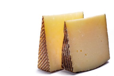 İki parça Manchego, queso manchego, İspanya 'nın La Mancha bölgesinde manchega soyundan gelen koyun sütünden yapılan peynir, beyaz üzerine izole edilmiş.