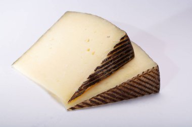 İki parça Manchego, queso manchego, İspanya 'nın La Mancha bölgesinde manchega soyundan gelen koyun sütünden yapılan peynir, beyaz üzerine izole edilmiş.
