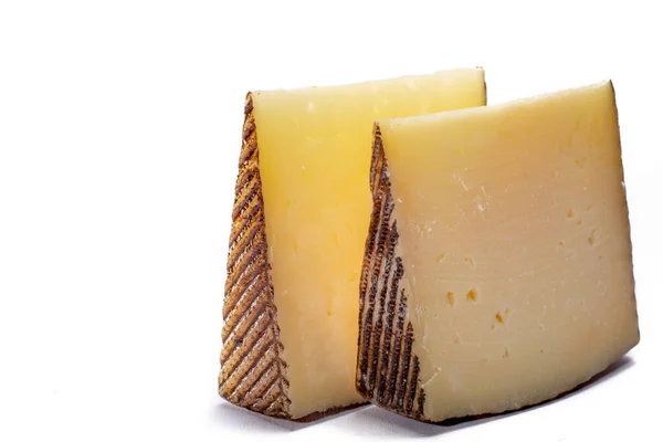 İki parça Manchego, queso manchego, İspanya 'nın La Mancha bölgesinde manchega soyundan gelen koyun sütünden yapılan peynir, beyaz üzerine izole edilmiş.