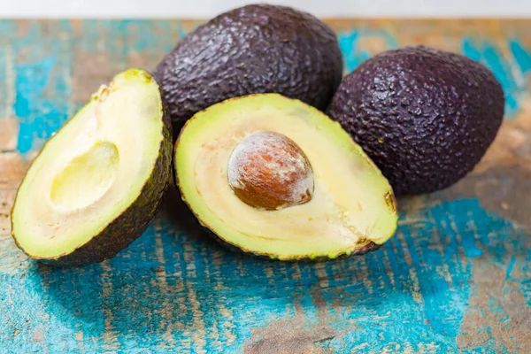 Rohe Reife Dunkelgrüne Ganze Avocados Mit Blättern Auf Holzgrund — Stockfoto