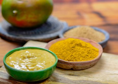 Lezzetli mango-köri sosu küçük kasede yenmeye hazır ve mango ve köri tozuyla kaplanmış.