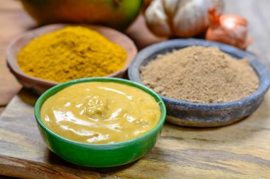 Lezzetli mango-köri sosu küçük kasede yenmeye hazır ve mango ve köri tozuyla kaplanmış.