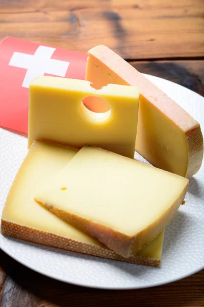 スイスチーズの盛り合わせ伝統的なチーズフォンデュやグラタン スイスの国旗に使われる丸みを帯びた穴 グリュイエール アペンセラー ラクレットを持つメンタルまたはエメンタール中ハードチーズ — ストック写真
