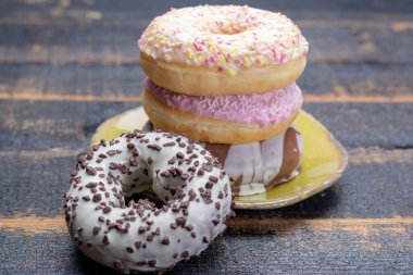 Siyah ahşap arka planda fırından alınmış renkli tatlı donutlar.