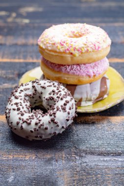 Siyah ahşap arka planda fırından alınmış renkli tatlı donutlar.
