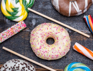 Çocuklar renkli çörekler ve ahşap masaya yakın şekerlerle parti yapıyorlar.