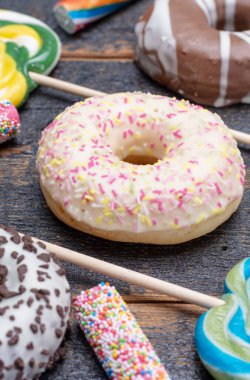 Çocuklar renkli çörekler ve ahşap masaya yakın şekerlerle parti yapıyorlar.