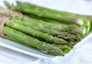 Beyaz tahtada taze çiğ yeşil kuşkonmaz var. Kapatın.