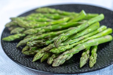 Siyah tahtada taze çiğ yeşil kuşkonmaz. Yakın plan.
