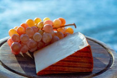 Kırmızı biber kaplı İspanyol keçi sütü peyniri ve olgun pembe üzümler yakın.