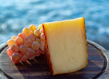 Kırmızı biber kaplı İspanyol keçi sütü peyniri ve olgun pembe üzümler yakın.