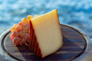 Kırmızı biber kaplı İspanyol keçi sütü peyniri ve olgun pembe üzümler yakın.