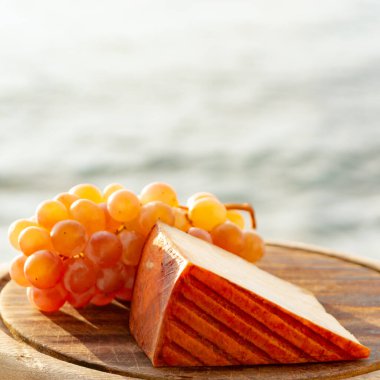 Kırmızı biber kaplı İspanyol keçi sütü peyniri ve olgun pembe üzümler yakın.