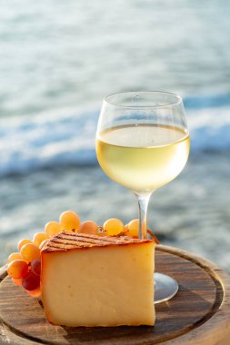 Kırmızı biber kaplı İspanyol keçi sütü peyniri ve açık terasta beyaz şarapla servis edilen olgun pembe masa üzümleri.