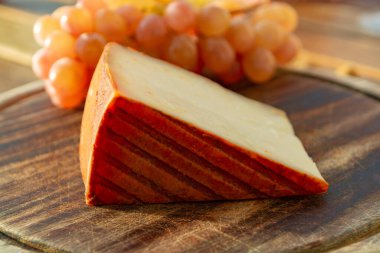 Kırmızı biber kaplı İspanyol keçi sütü peyniri ve olgun pembe üzümler yakın.