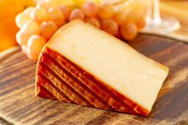 Kırmızı biber kaplı İspanyol keçi sütü peyniri ve olgun pembe üzümler yakın.