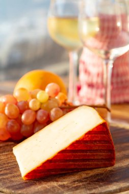 Kırmızı biber kaplı İspanyol keçi sütü peyniri ve açık terasta beyaz şarapla servis edilen olgun pembe masa üzümleri.
