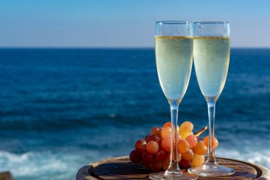 Şampanya, kovboyculuk ya da kava, iki bardak pembe üzümle servis edilir, terasta deniz manzaralı, yakından.