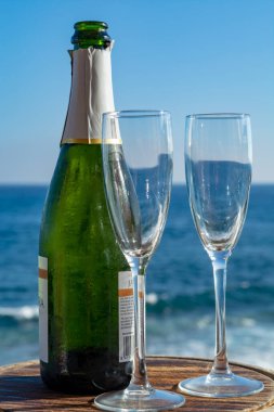 Şampanya, Prosecco ya da Cava şişesi, terasta servis edilen deniz manzaralı iki bardak.