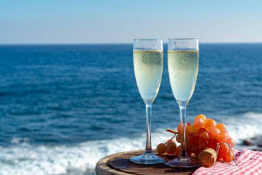 Şampanya, kovboyculuk ya da kava, iki bardak pembe üzümle servis edilir, terasta deniz manzaralı, yakından.