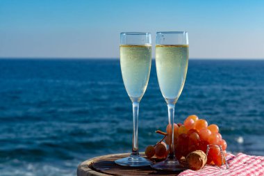 Şampanya, kovboyculuk ya da kava, iki bardak pembe üzümle servis edilir, terasta deniz manzaralı, yakından.