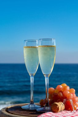 Şampanya, kovboyculuk ya da kava, iki bardak pembe üzümle servis edilir, terasta deniz manzaralı, yakından.