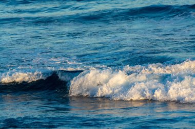 Koyu mavi okyanus suları günbatımında kapanır.