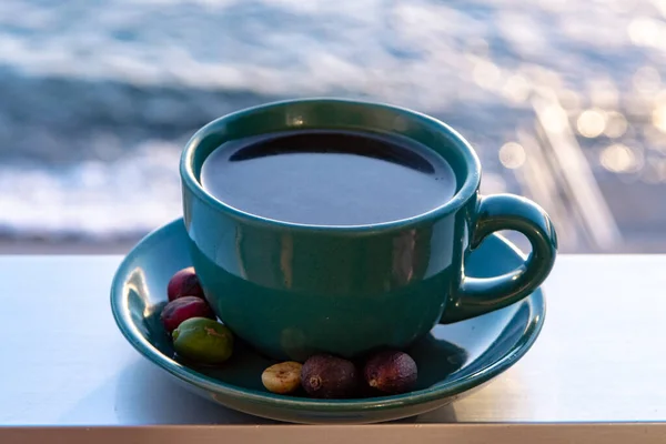 Cup with black coffee served outside with sea view close up