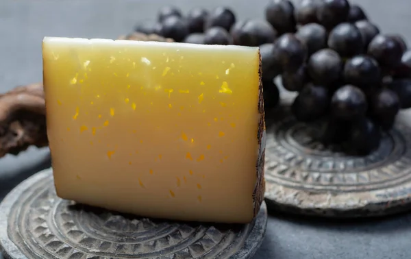 スペインのハードチーズミルクチーズのピースマンチェゴはブラックブドウで提供していますクローズアップ — ストック写真