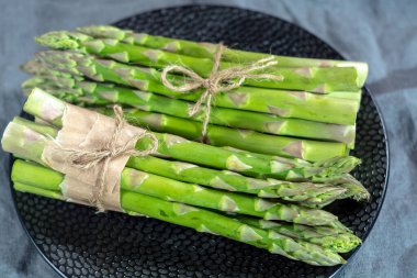 Siyah tahtada taze çiğ yeşil kuşkonmaz. Yakın plan.