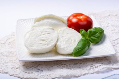 Yumuşak beyaz İtalyan peyniri Mozzarella bufalosu taze domates ve yeşil fesleğen yapraklarıyla servis edilir.
