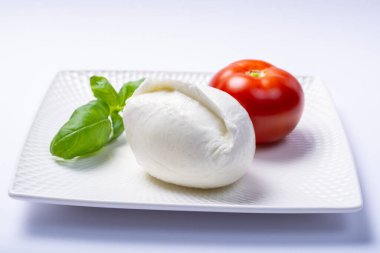 Yumuşak beyaz İtalyan peyniri Mozzarella bufalosu taze domates ve yeşil fesleğen yapraklarıyla servis edilir.