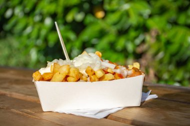 Dışarıda taze kızarmış Belçika patatesleri, ketçap ve sosla servis ediliyor.