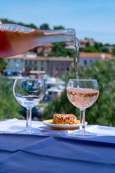 Waiter pouring cold rose wine on outdoor cafe terrace in sunny summer day in Provence, France