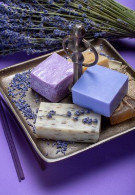Doğal sağlıklı aromaterapi ve organik Fransız lavantası ile cilt tedavisi, mor arka planda lavanta sabunu ve kurumuş lavanta çiçekleri.