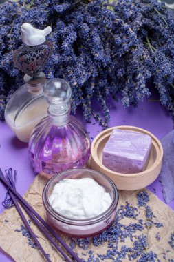 Doğal sağlıklı aromaterapi ve organik Fransız lavantası, lavanta sabunu, yüz kremi ile cilt tedavisi mor arka planda kurutulmuş lavanta çiçekleriyle birlikte gerekli yağlar.